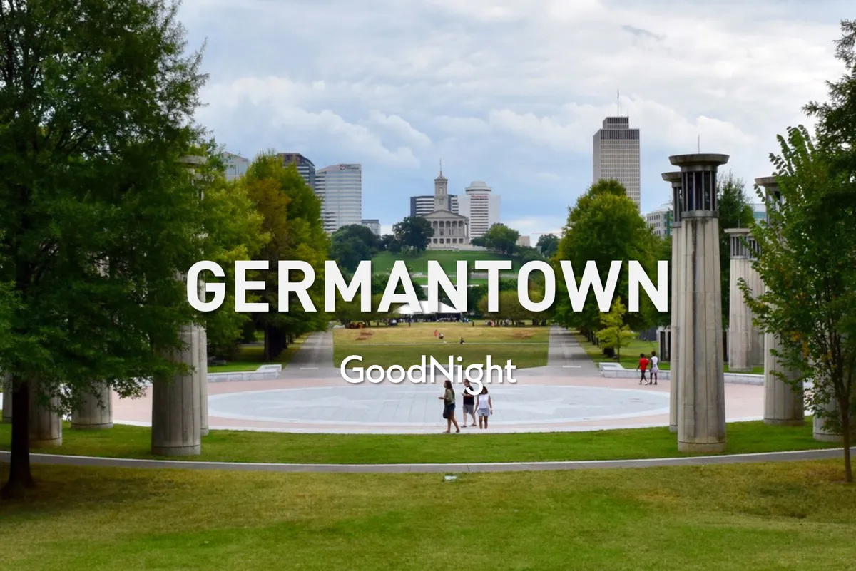 A peaceful city park scene featuring a green lawn, tree-lined paths, a circular plaza, and the Nashville skyline in the background. The image suggests families enjoying evening strolls, picnics, or community gatherings in spacious, welcoming green spaces.