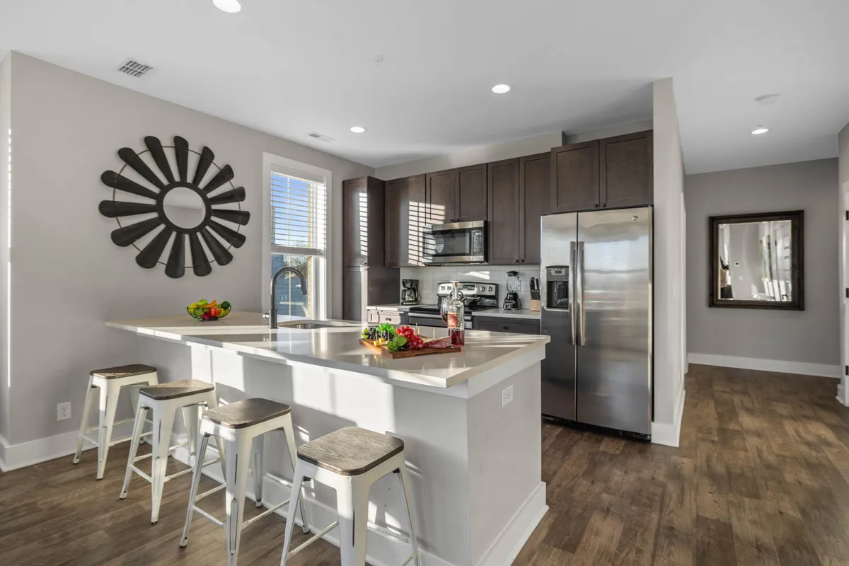 A modern kitchen island with stainless steel appliances, a decorative mirror, sunburst wall art, and open sightlines to connected living spaces. The island is ready for meal prep and socializing, creating a vibrant focal point for gatherings and celebrations.