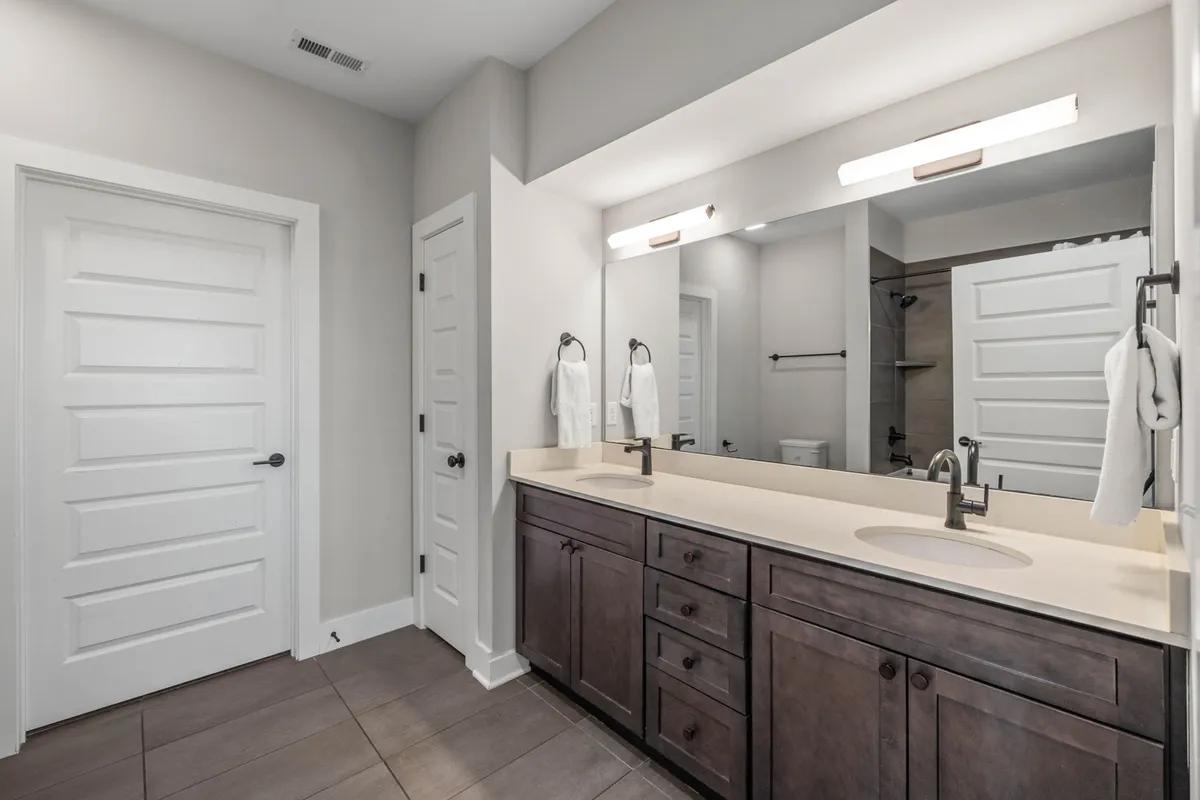 A modern, calm bathroom with a double-sink vanity, a large mirror, and sleek fixtures. The space is bright and spacious, designed for comfortable morning or evening routines.