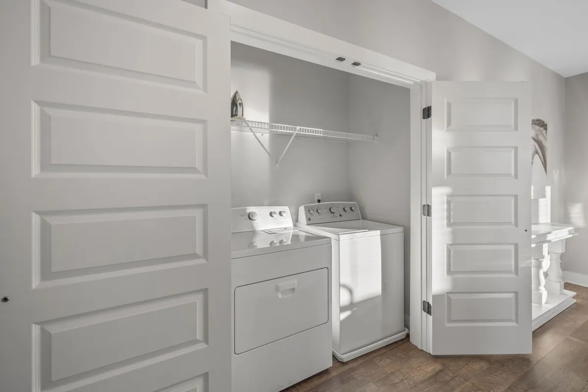 This utility space features a washing machine and dryer with shelving above for supplies, emphasizing an organized, practical setup for guests to handle laundry needs during their stay.